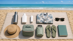 Ten beach essentials arranged on a beach blanket by the ocean
