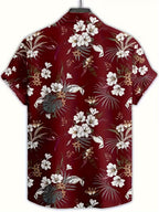 A short-sleeve button-up camp shirt with a red-burgundy tropical floral print, featuring white hibiscus flowers, green palm leaves, and brown accents, displayed on a hanger against a white background.