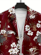 A red tropical floral print blazer with white flowers and green palm leaves, styled open over a white t-shirt on a black hanger with a silver pendant necklace.