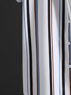 A close-up of a white button-front garment with vertical stripes in black, navy, brown, and light blue, shown against a dark textured background.