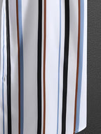 A close-up of a white fabric with vertical stripes in black, brown, light blue, and a thin red stripe, next to a dark gray textured surface.