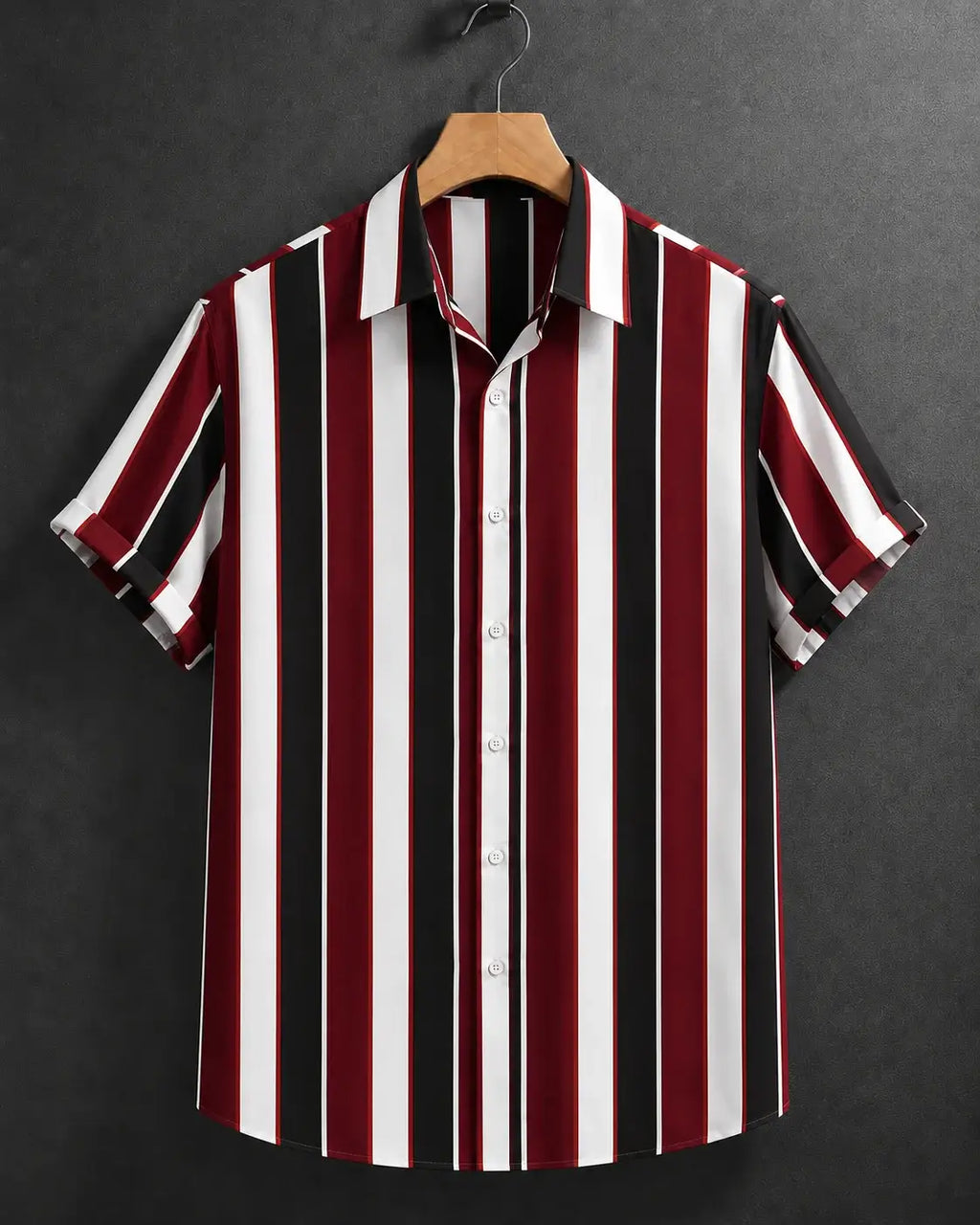 A short-sleeve button-up shirt with vertical stripes in burgundy red, black, and white, hanging on a wooden hanger against a dark gray textured background.
