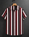A short-sleeve button-up shirt with vertical stripes in burgundy red, black, and white, hanging on a wooden hanger against a dark gray textured background.