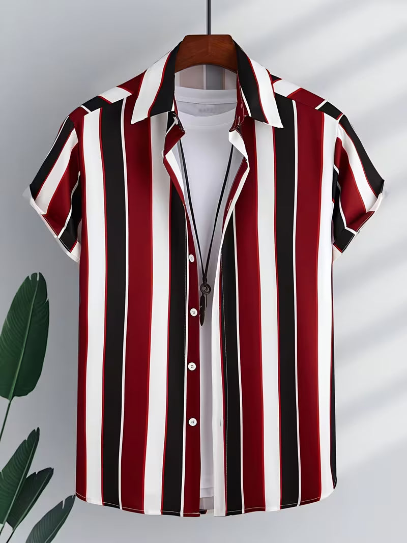 A short-sleeve button-up shirt with vertical red, black, and white stripes, hanging on a wooden hanger against a light gray wall with leaf shadows and a green plant leaf visible on the left.