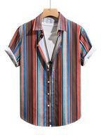 A men's short-sleeve button-up shirt with a vertical striped pattern in brown, red, blue, and white, styled on a wooden hanger over a white t-shirt against a plain white background.