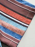 A close-up of a striped fabric with textured horizontal bands in blue, rust orange, brown, black, and white, laid flat on a light gray surface.