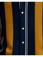 Close-up of a button-front shirt with vertical stripes in navy blue, mustard yellow, and thin white pinstripes.