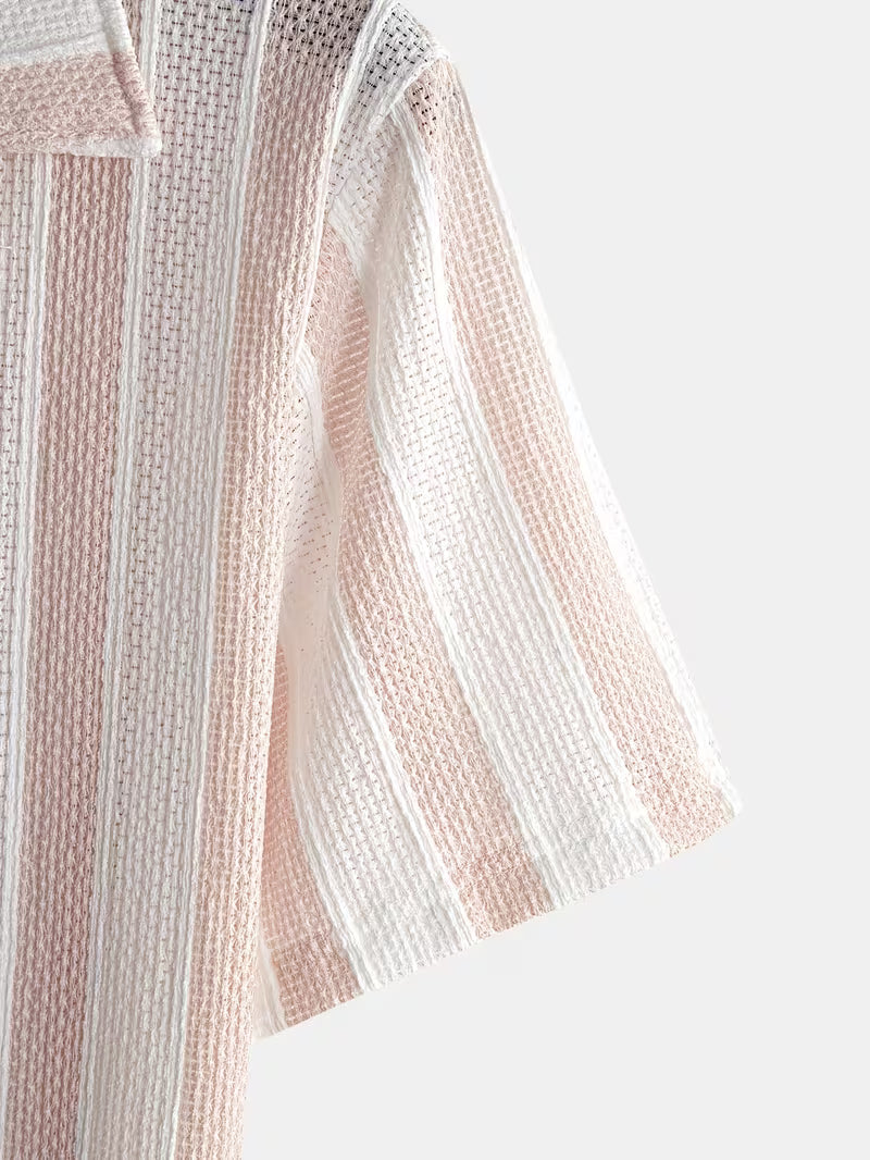 A close-up of a short-sleeve button-up shirt featuring vertical stripes in soft blush pink and white, with a textured knit pattern and a visible collar.