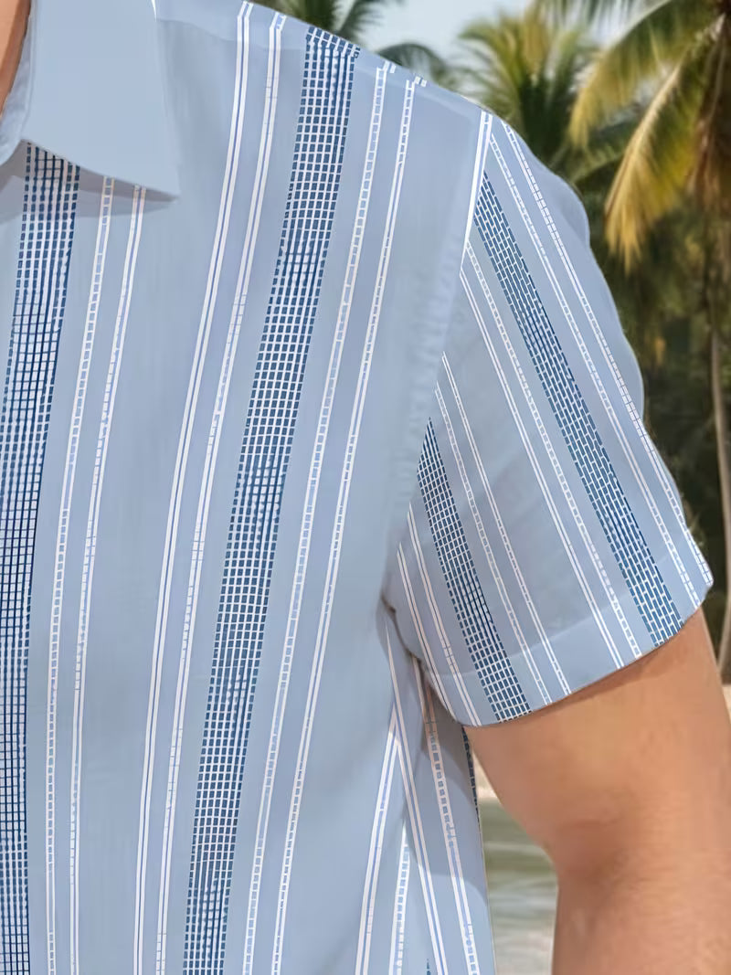 A close-up of a man wearing a light blue short-sleeve button-up shirt with vertical white and navy striped patterns, set against a tropical beach background with palm trees.