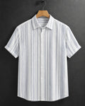 A short-sleeve button-up shirt with vertical blue and white stripes, hanging on a wooden hanger against a dark gray background.