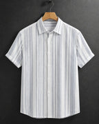 A short-sleeve button-up shirt with vertical blue and white stripes, hanging on a wooden hanger against a dark gray background.