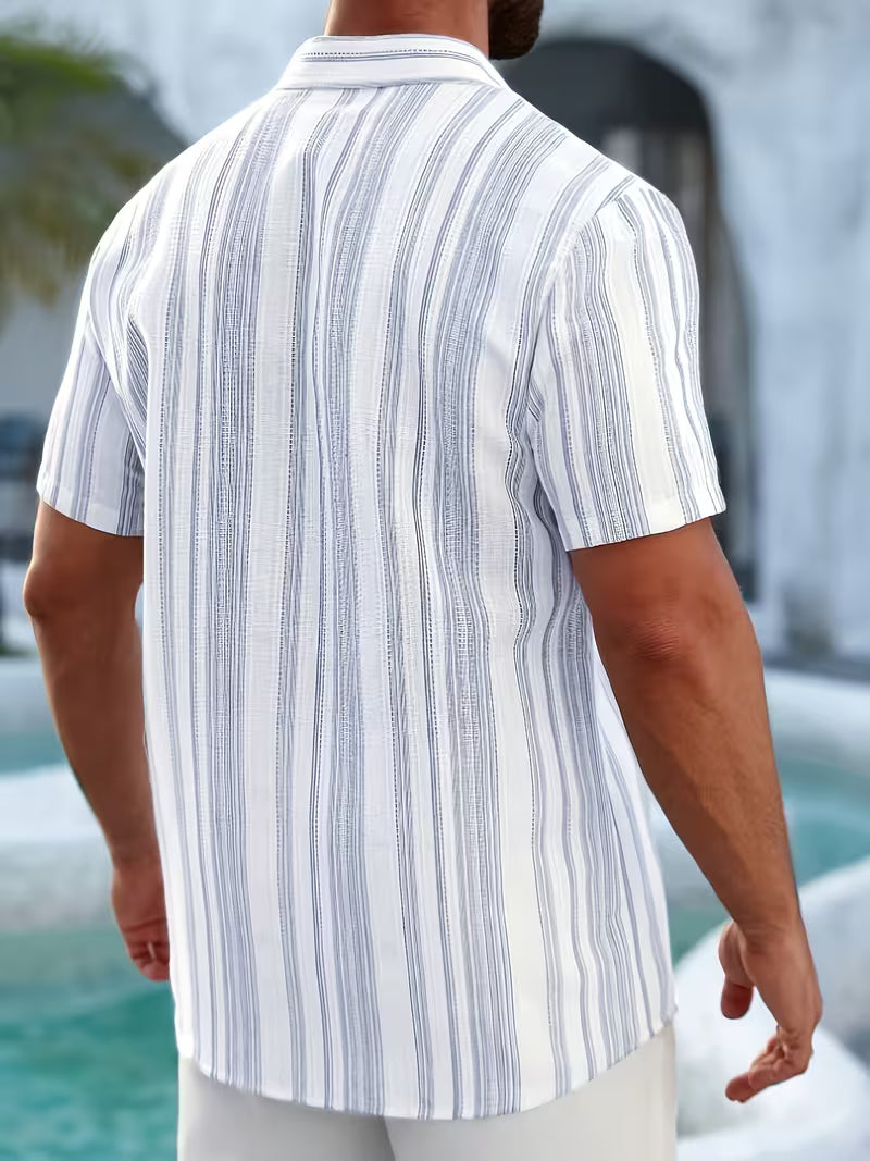 A man viewed from behind wearing a short-sleeve button-up shirt with vertical white and light blue stripes, standing outdoors near a pool.
