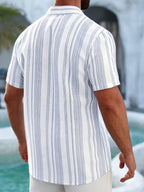 A man viewed from behind wearing a short-sleeve button-up shirt with vertical white and light blue stripes, standing outdoors near a pool.