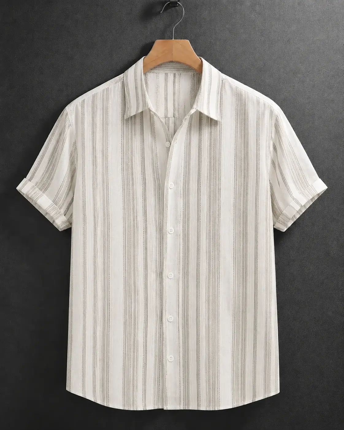 A short-sleeve button-up shirt with vertical beige and brown stripes on an off-white base, hanging on a wooden hanger against a dark textured background.