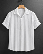 A white short-sleeve button-up shirt with thin vertical gray stripes, hanging on a wooden hanger against a dark gray textured background.