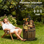 A man relaxes in a wooden folding chair on a grassy lawn beside a decorative barrel fountain with water flowing from a small tree branch spout. The scene is set in a garden with flowers and trees, with promotional text reading 'Promotes relaxation', 'Improves concentration and enhances overall comfort', '55dB', and a soundwave graphic.