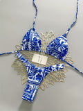 Blue and white patterned bikini set with gold accents on a gray background