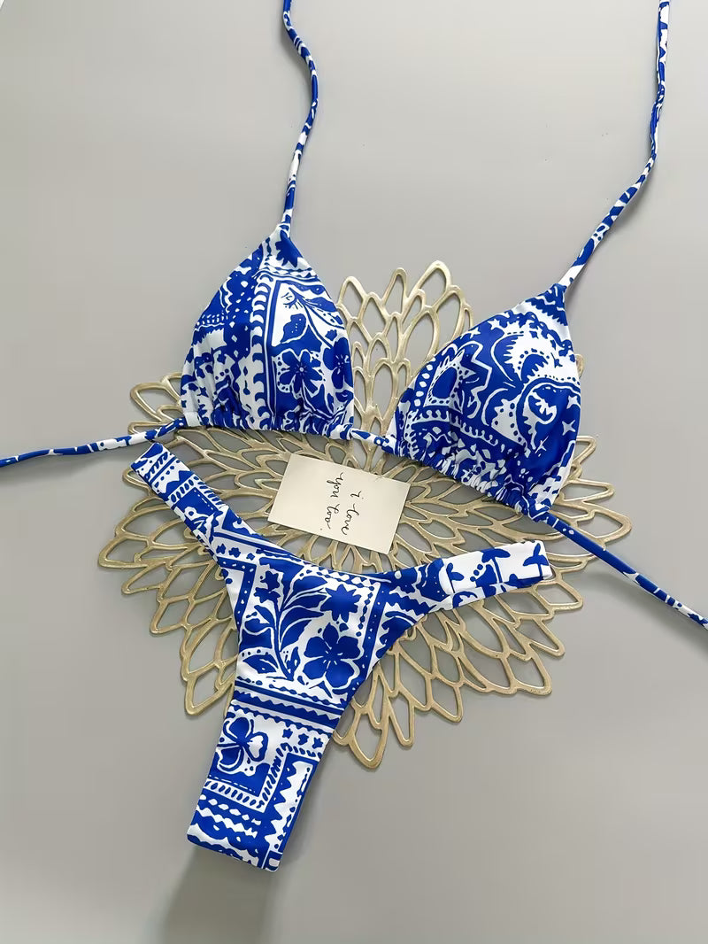 Blue and white patterned bikini set with gold accents on a gray background