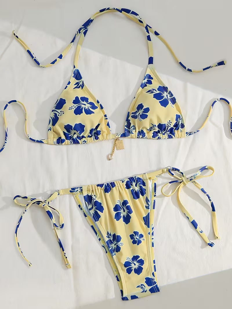 A two-piece string bikini set with a yellow base and blue floral print, laid flat on a white background.