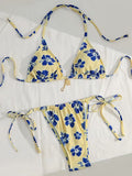 A two-piece string bikini set with a yellow base and blue floral print, laid flat on a white background.