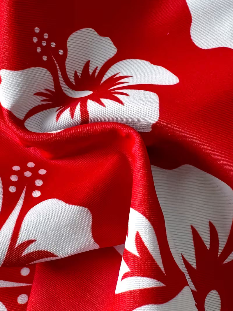 A close-up of red fabric with a bold white hibiscus floral print, showing the material's texture and folds.