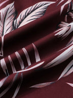 A close-up of draped fabric with a deep burgundy base and a large white tropical leaf print.