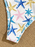 White bikini bottom with a colorful starfish print in blue, yellow, and pink, laid flat on a woven straw surface.