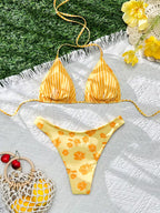 Yellow bikini set with floral pattern on a textured surface with flowers and berries.