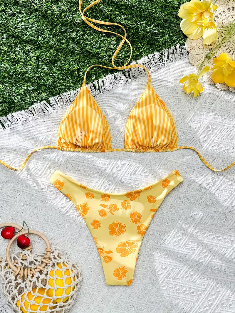 Yellow bikini set with floral pattern on a textured surface with flowers and berries.